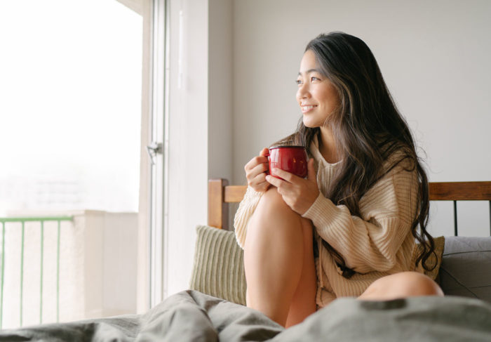 Woman enjoying a cup of coffee in bed.